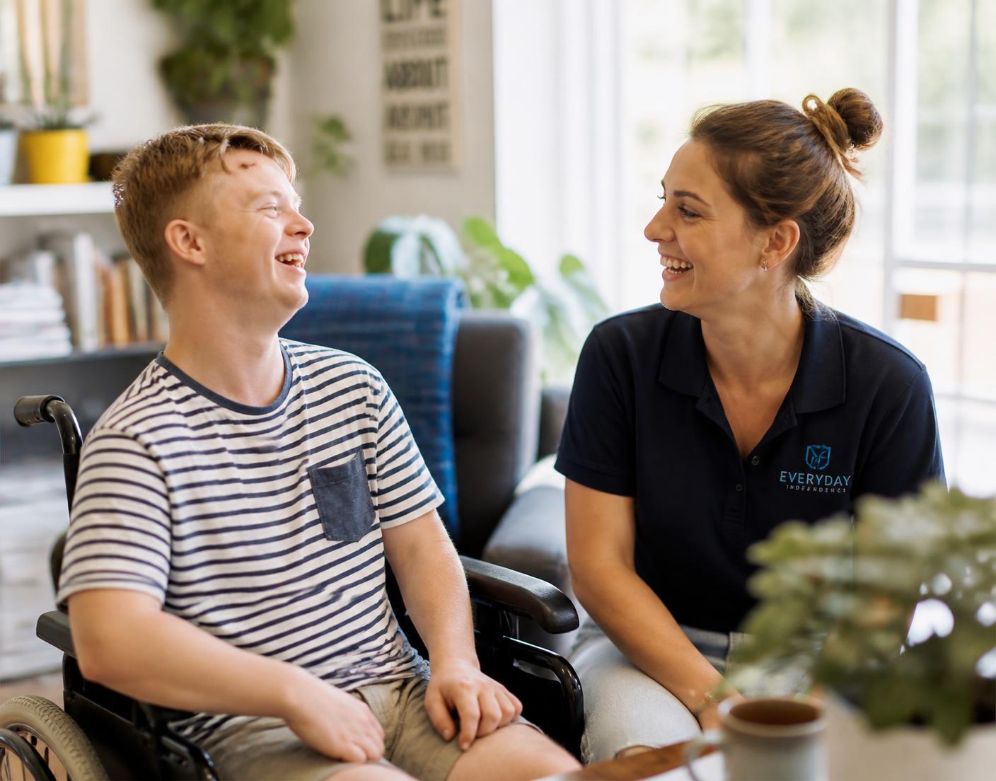 A support worker and a participant laughing together in a bright living room